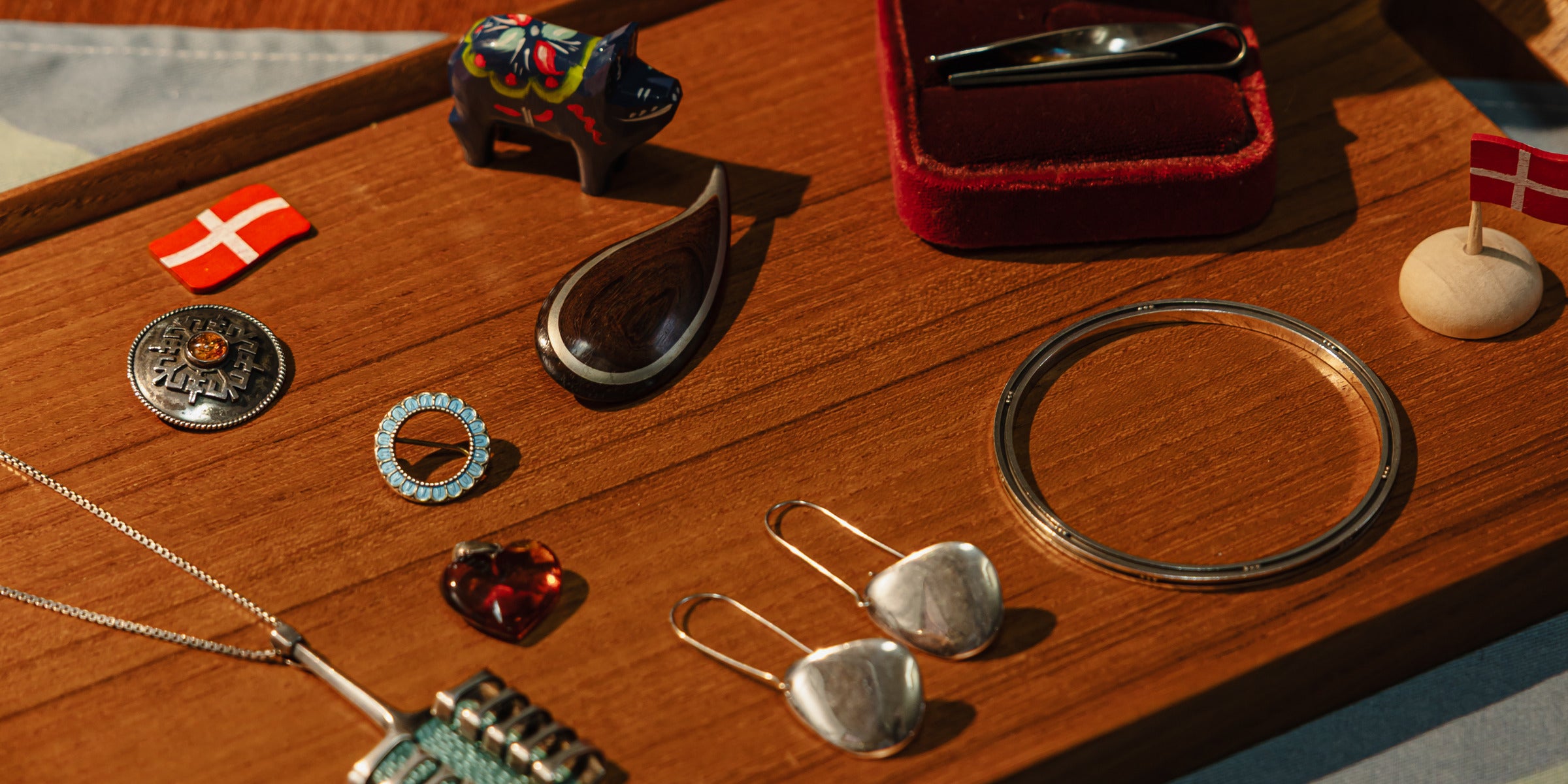 Silver and enamel jewellery laid out on a teak tray
