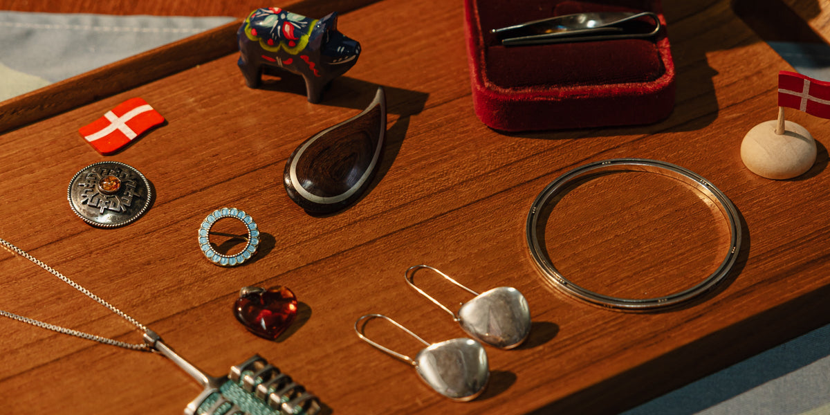 Silver and enamel jewellery laid out on a teak tray
