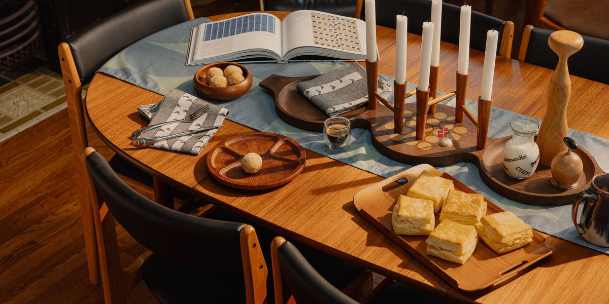 A Danish teak dining table set for coffee: candelabrum, open book, biscuits on a tray