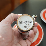 DeSimone hand-painted espresso cups and saucers, held in a hand for scale