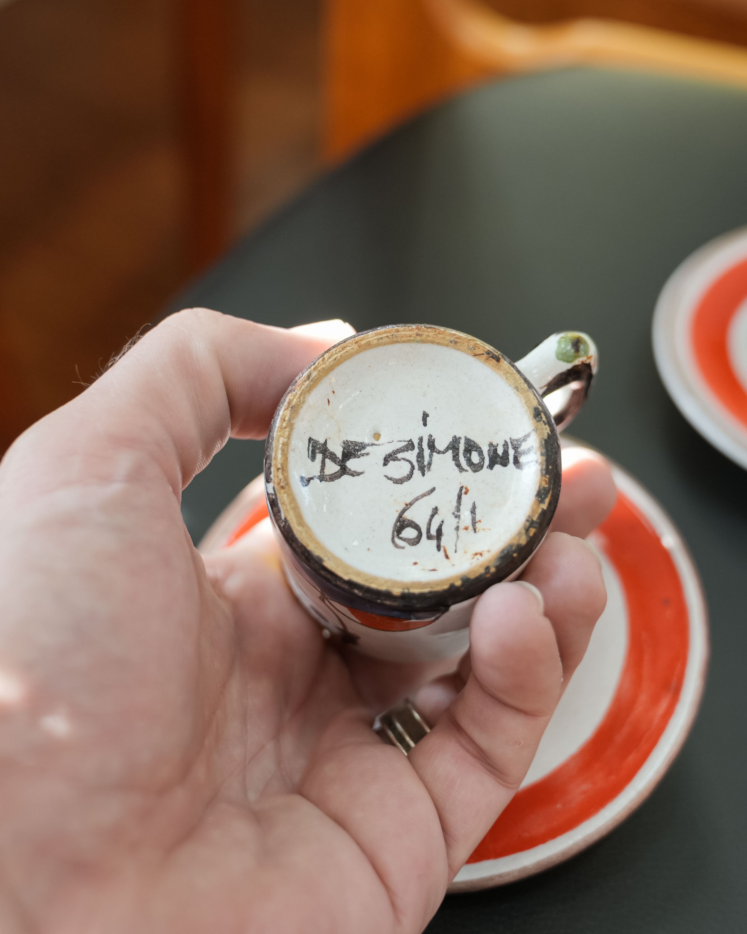 DeSimone hand-painted espresso cups and saucers, held in a hand for scale