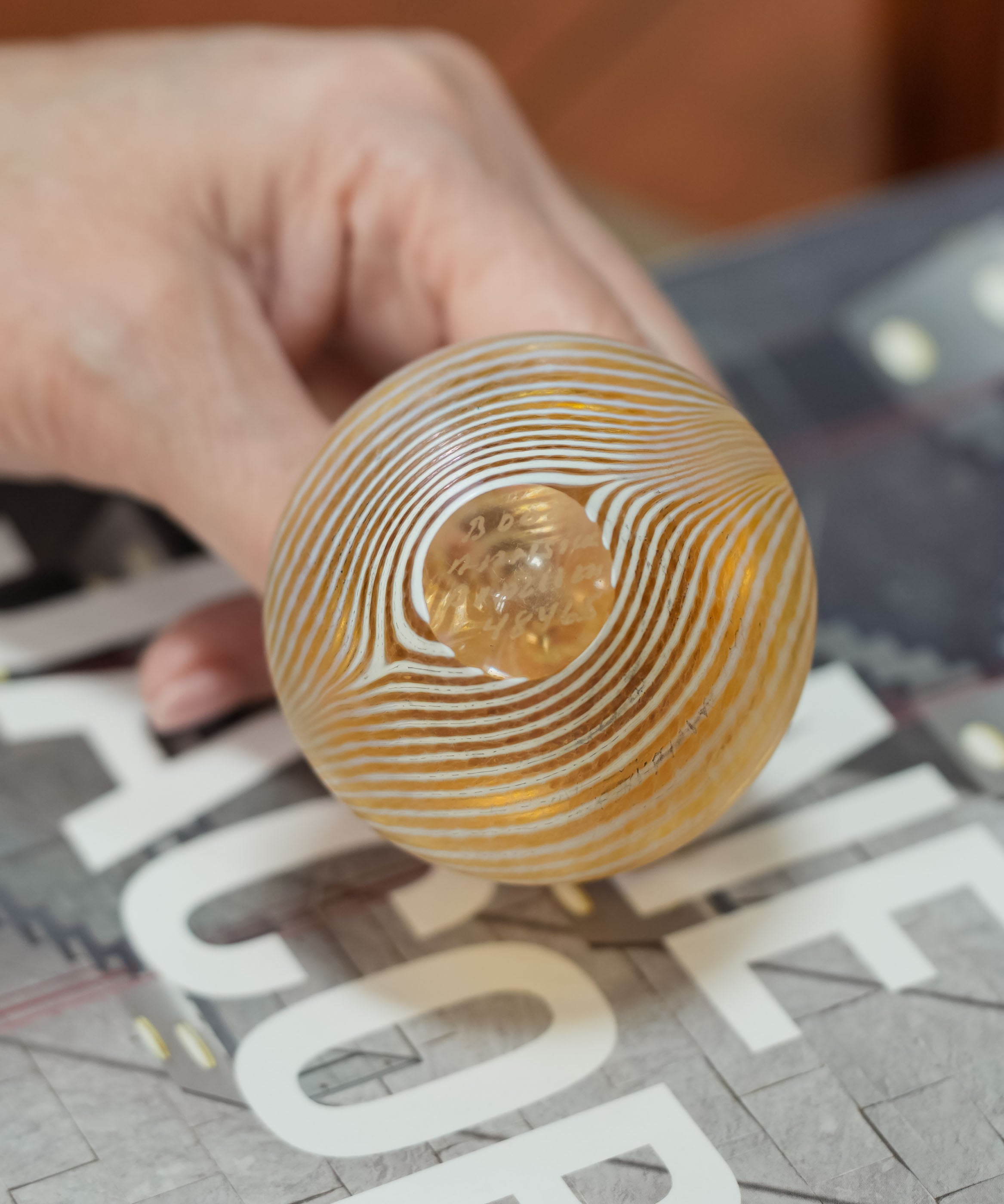 Base of the Kosta Boda miniature vase held in a hand, showing the polished pontil and the feathered stripes